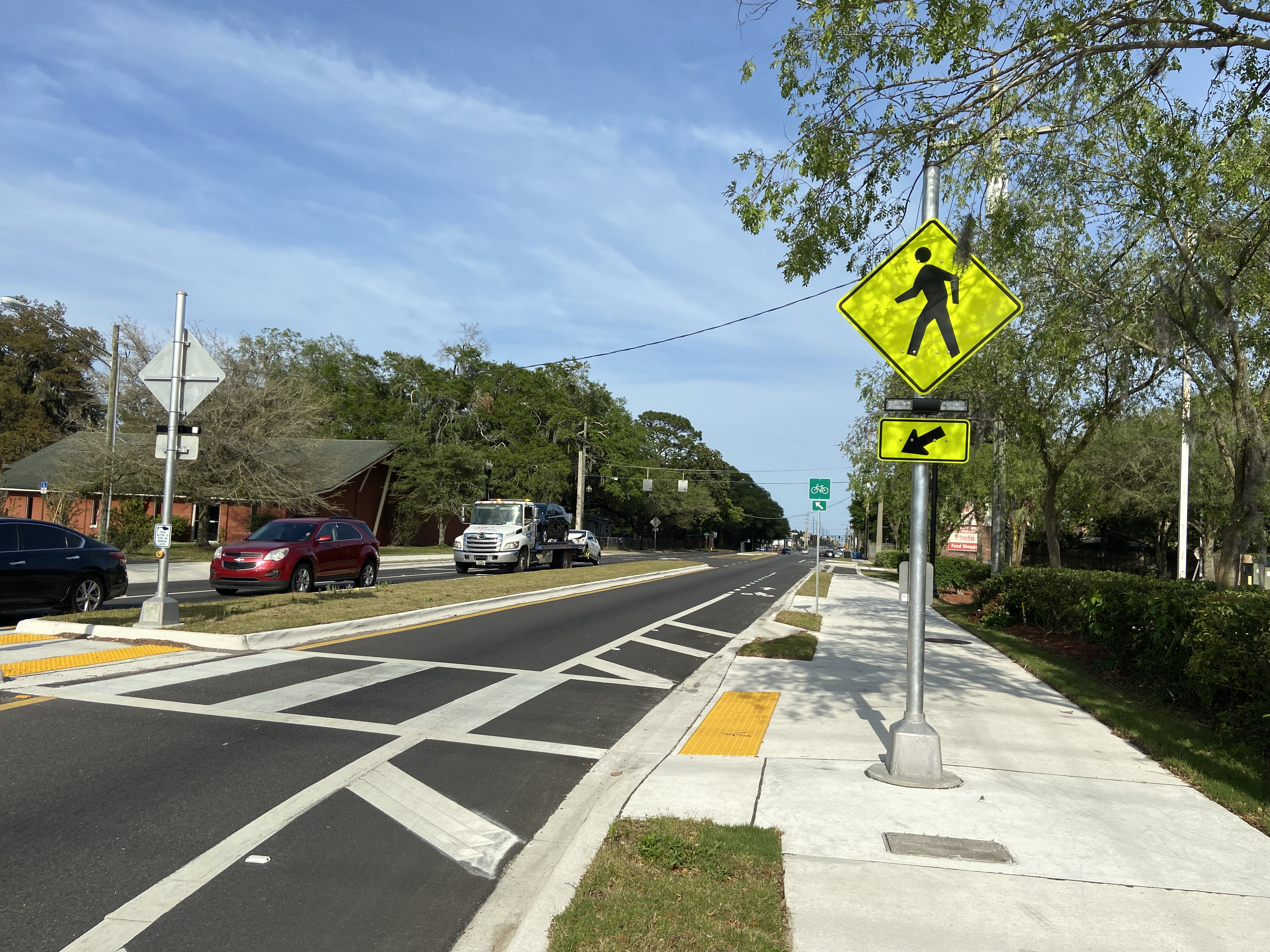 Road with cars stopped at a crosswalk with a yellow pedestrian crossing sign. Image Credit: FHWA
